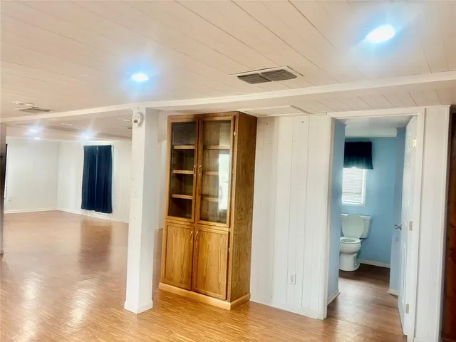 a view of a hallway with wooden floor and a bathroom