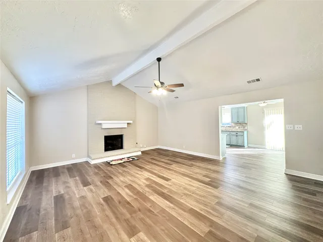 a view of an empty room with window and wooden floor