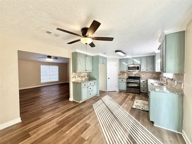 a kitchen view with stainless steel appliances kitchen island granite countertop a stove refrigerator and cabinets