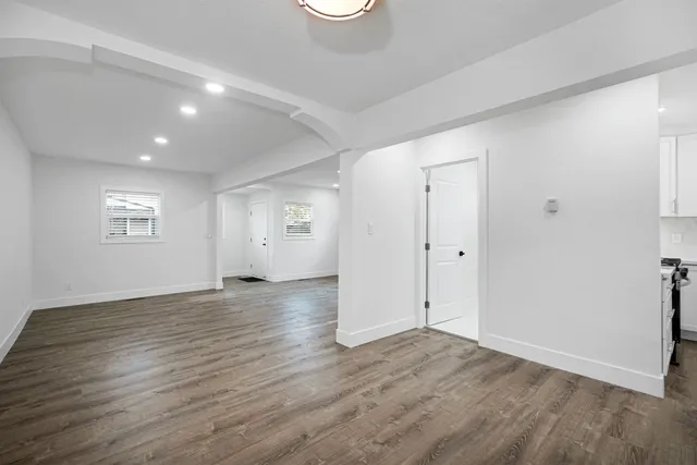 an empty room with wooden floor and windows