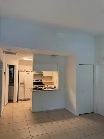 a kitchen with granite countertop a refrigerator and a stove top oven