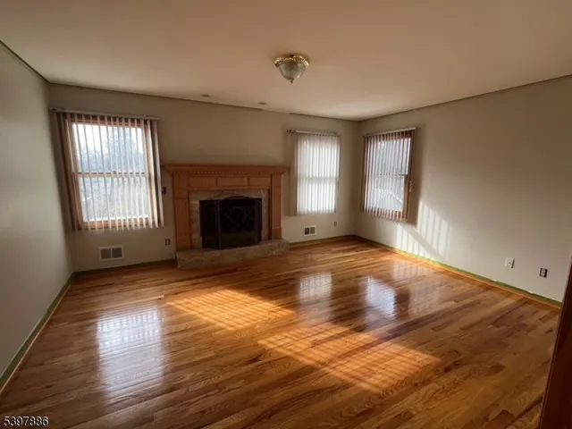 a view of empty room with wooden floor and fireplace