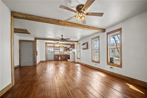 a view of an empty room with window and wooden floor