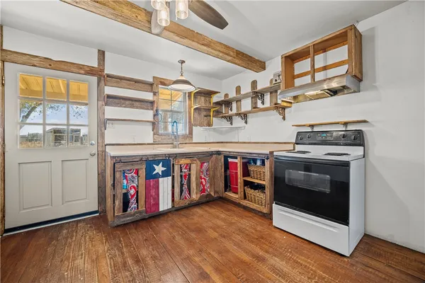 a kitchen with stove and wooden floor
