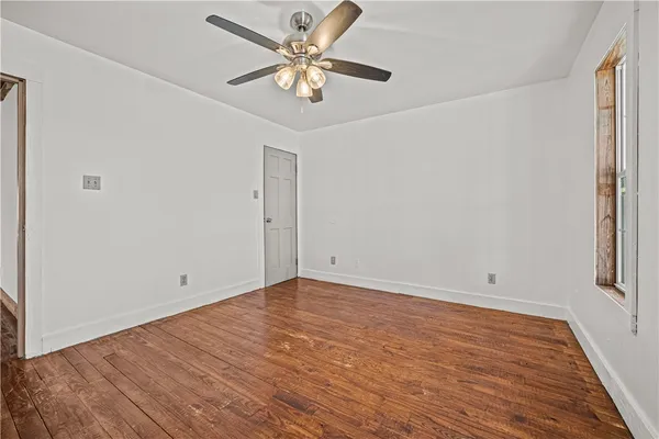 an empty room with wooden floor and ceiling fan
