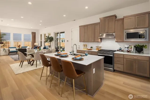 a kitchen with stainless steel appliances granite countertop a table chairs sink and cabinets