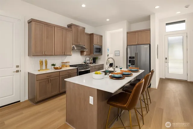 a kitchen with a sink a stove a refrigerator and white cabinets with wooden floor