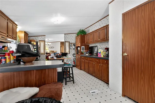 a kitchen with stainless steel appliances kitchen island granite countertop a sink a microwave cabinets and a dining table