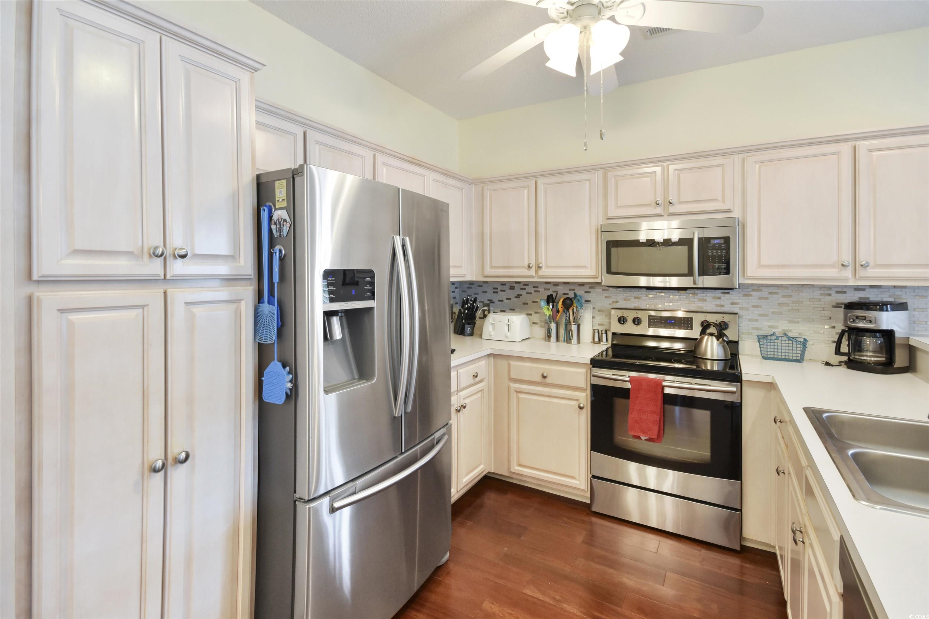 4502 Sweetwater Boulevard, Unit 4502 Murrells Inlet, SC 29576 - Photo 8 of 28 Kitchen with appliances with stainless steel finishes, light countertops, dark wood finished floors, and decorative backsplash