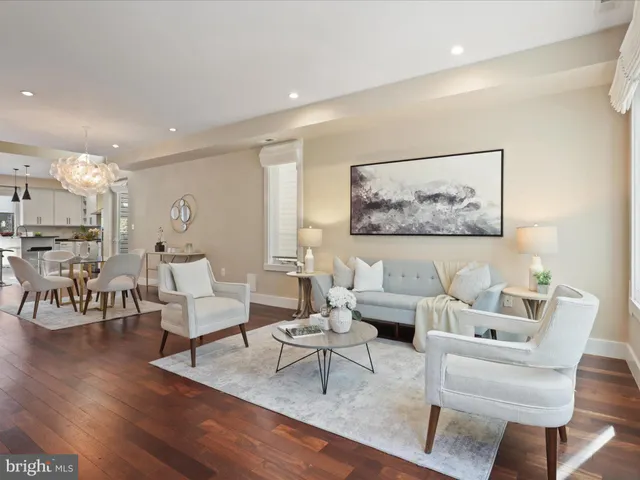 a living room with furniture kitchen view and a wooden floor