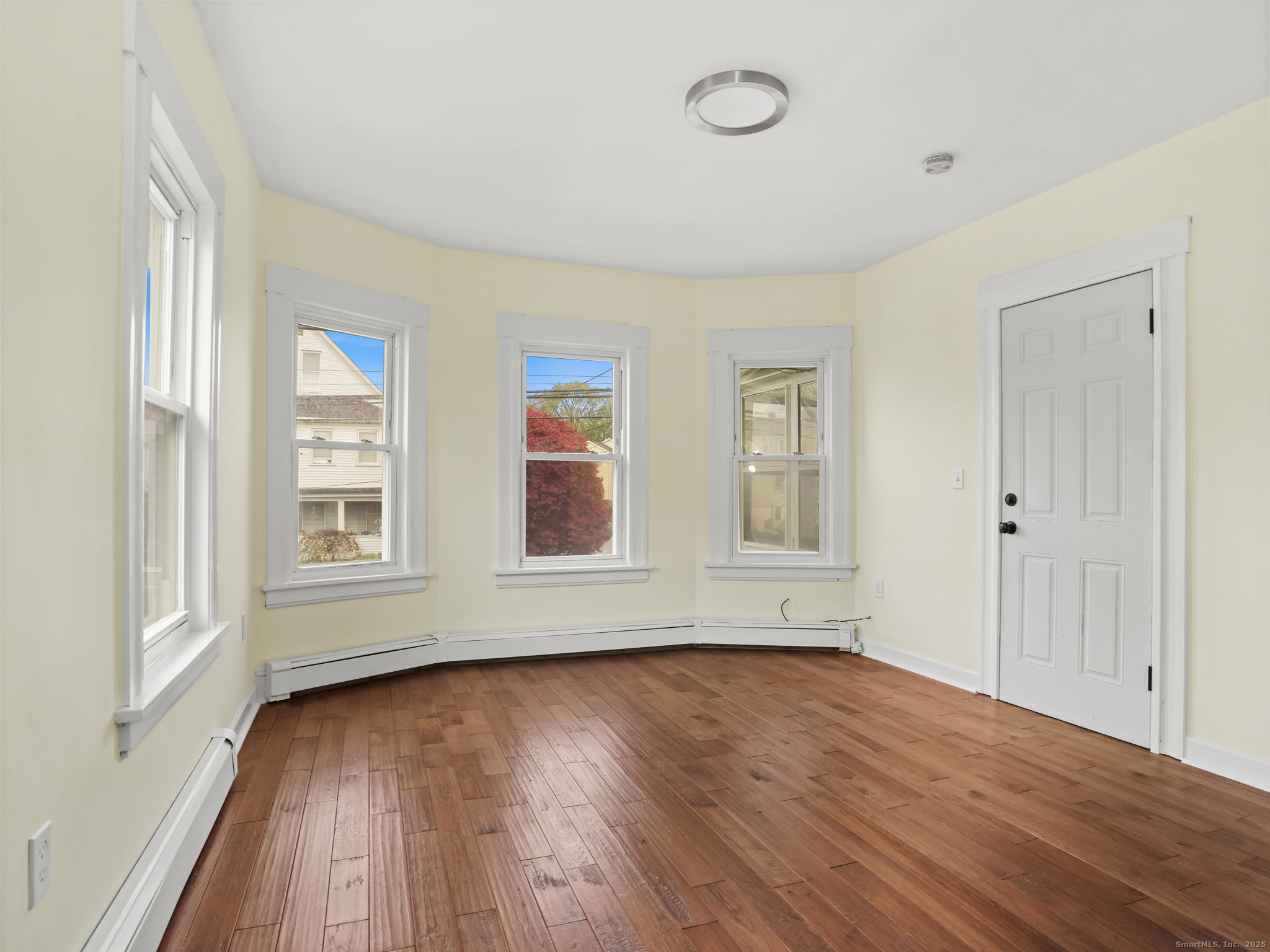 90 Amsterdam Avenue, Unit 1 Bridgeport, CT 06606 - Photo 5 of 14 an empty room with wooden floor and windows