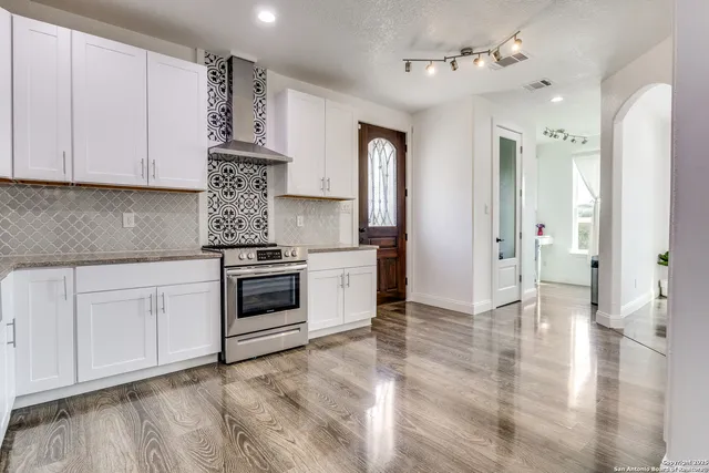 a kitchen with stainless steel appliances granite countertop a stove a sink and a refrigerator with white cabinets