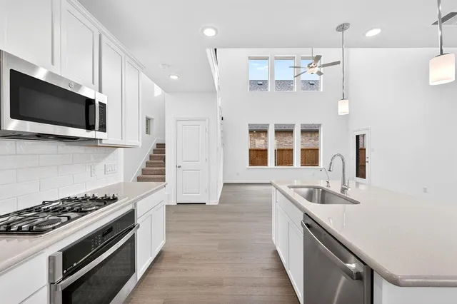 a kitchen with stainless steel appliances a stove a sink and a microwave