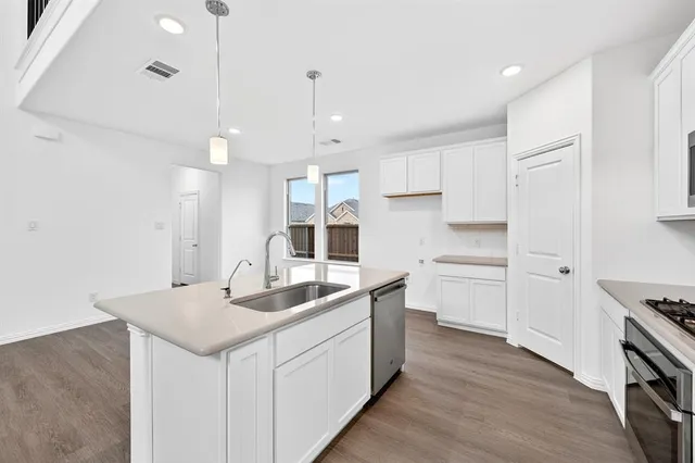 a kitchen with a sink stove and wooden floor