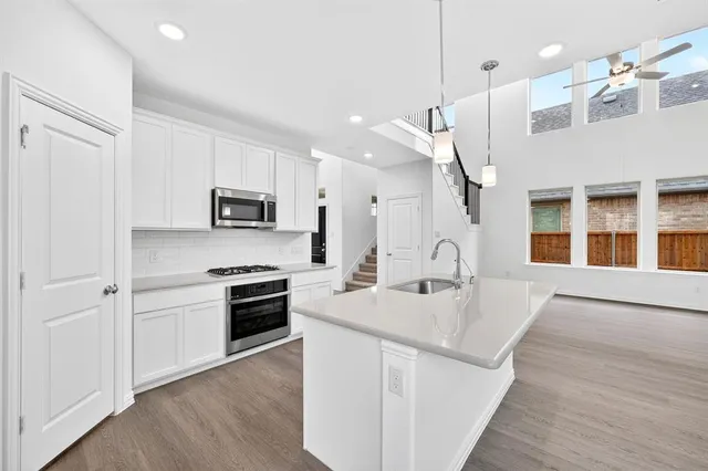 a kitchen with stainless steel appliances granite countertop a sink dishwasher a refrigerator and a stove with wooden floor