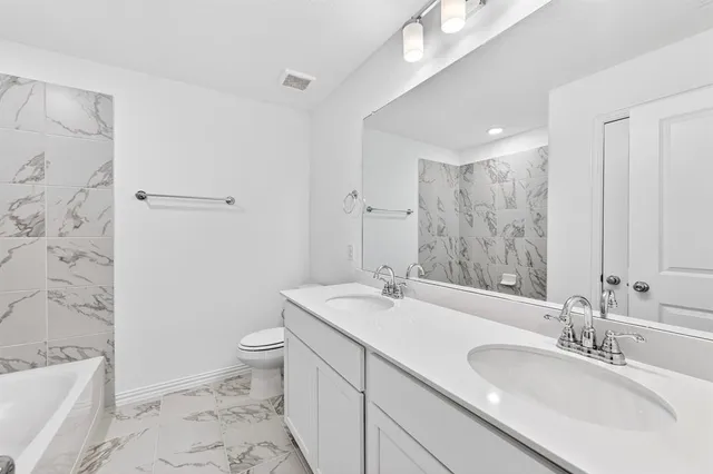 a bathroom with a granite countertop sink a toilet and shower