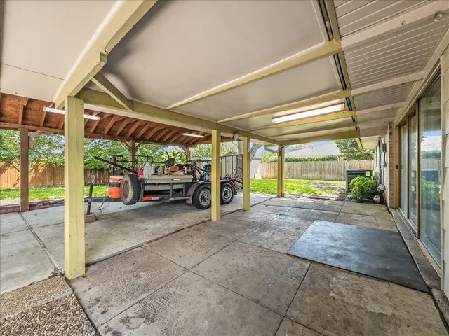 a view of a patio with a table and chairs under an umbrella with large trees