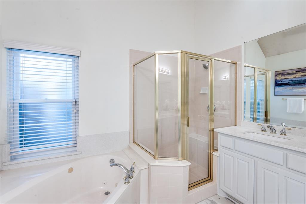 3752 Park Place Addison, TX 75001 - Photo 17 of 25 The bathroom features a built-in jetted tub, a corner shower with a glass enclosure, and a vanity with a sink and mirror