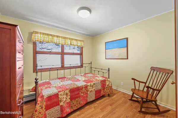 a bedroom with a bed chair and two windows