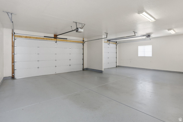 2190 750 West Perry, UT 84302 - Photo 34 of 42 Spacious garage featuring two overhead doors, a window, concrete flooring, and fluorescent lighting