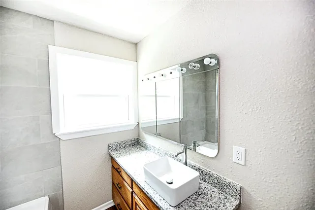 a bathroom with a sink vanity granite and a mirror