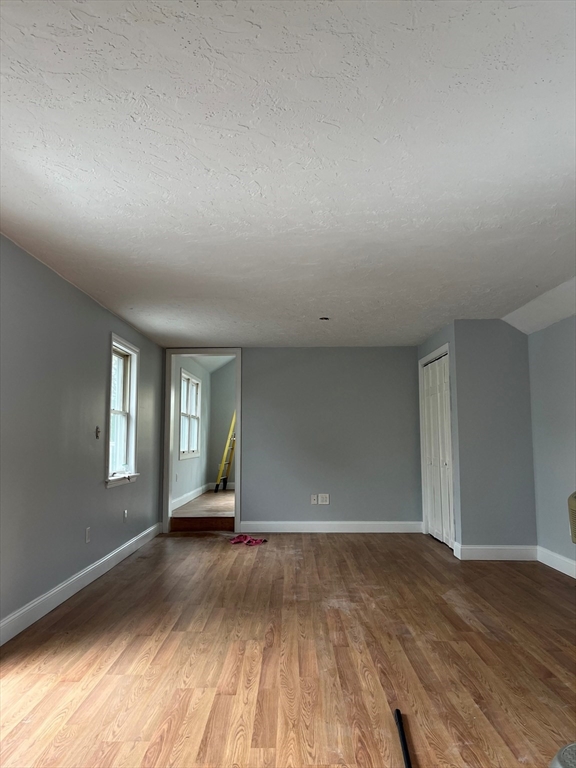 17 Hill Street, Unit 2 Quincy, MA 02169 - Photo 2 of 8 an empty room with wooden floor and windows