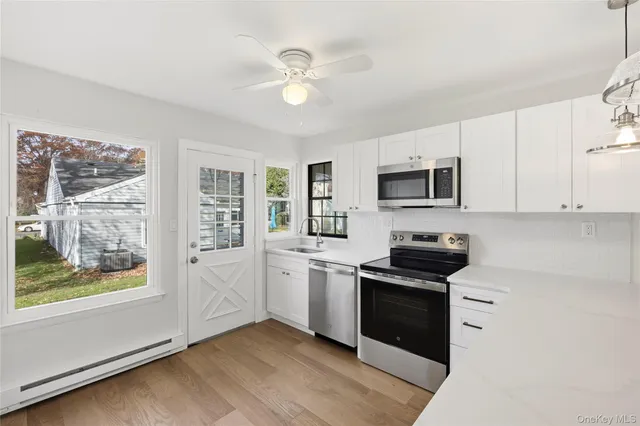a kitchen with cabinets stainless steel appliances and a window