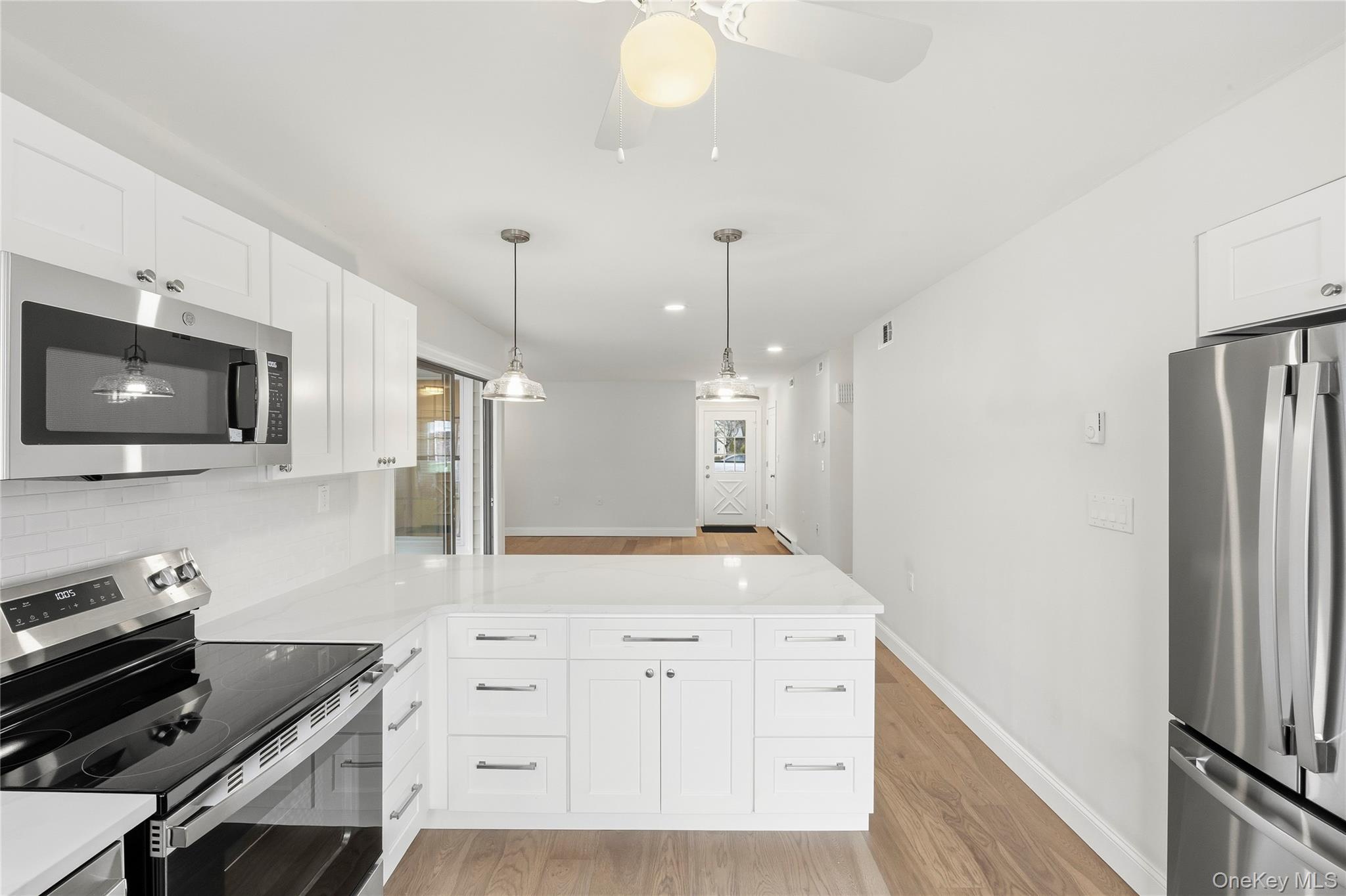 145 Edinburgh Drive Ridge, NY 11961 - Photo 5 of 13 a kitchen with white cabinets and stainless steel appliances