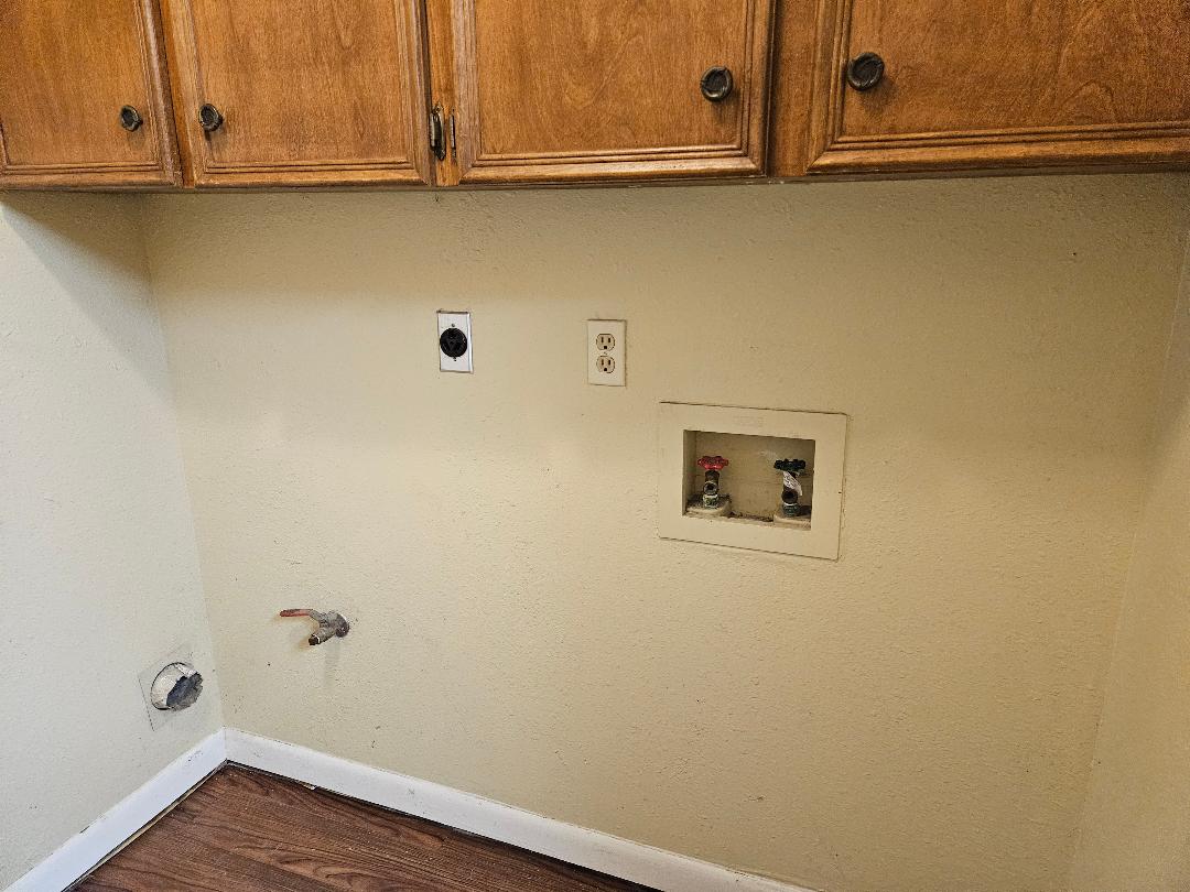 16 North Ave A, Unit B Elgin, TX 78621 - Photo 13 of 17 Utility area featuring overhead wooden cabinetry with dark hardware, hard surface flooring, and wall-mounted water and electrical hookups