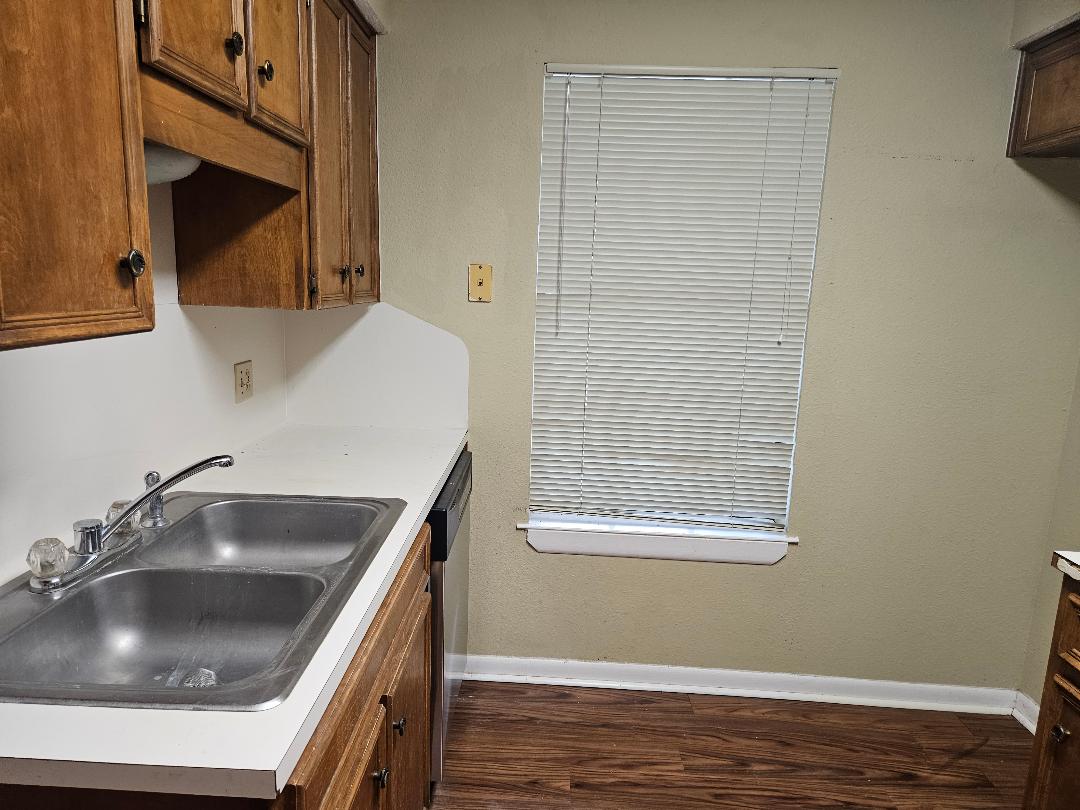 16 North Ave A, Unit B Elgin, TX 78621 - Photo 4 of 17 The kitchen features wood cabinetry, a dual basin stainless steel sink, and a window with blinds