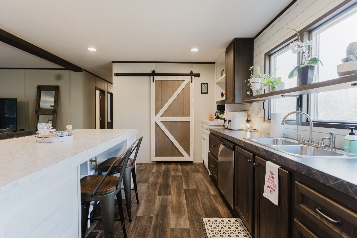 400 St Johns Road Dale, TX 78616 - Photo 5 of 17 Kitchen featuring a barn door, dark brown cabinets, dark wood-style floors, a kitchen breakfast bar, and recessed lighting