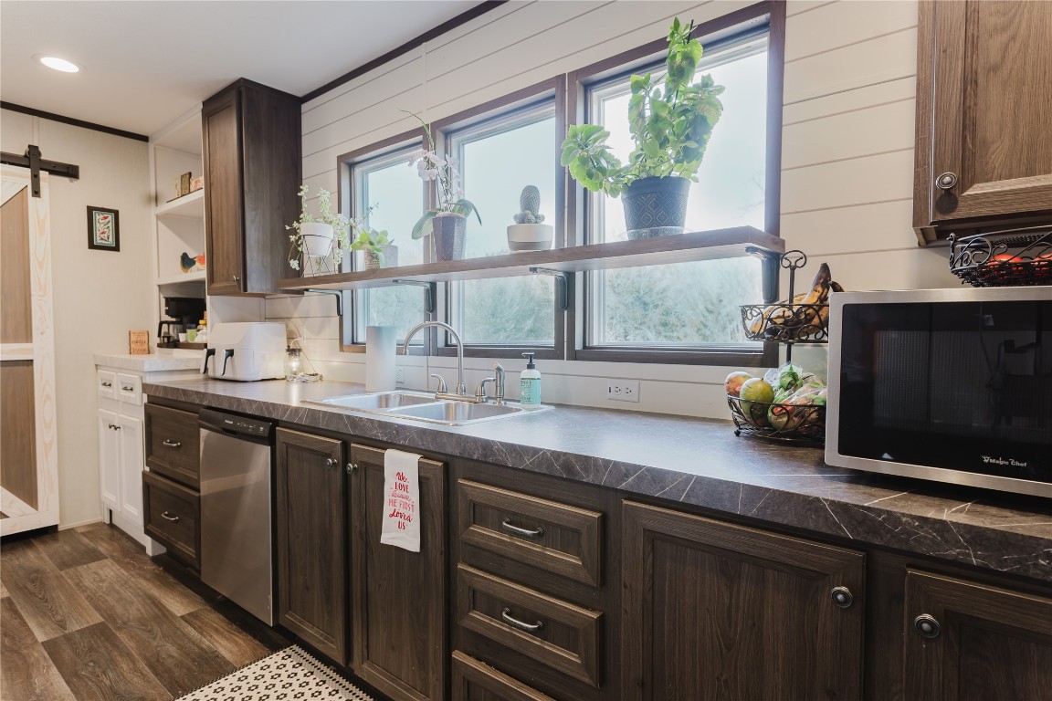 400 St Johns Road Dale, TX 78616 - Photo 6 of 17 Kitchen featuring a barn door, dark brown cabinets, stainless steel appliances, dark countertops, and dark wood finished floors