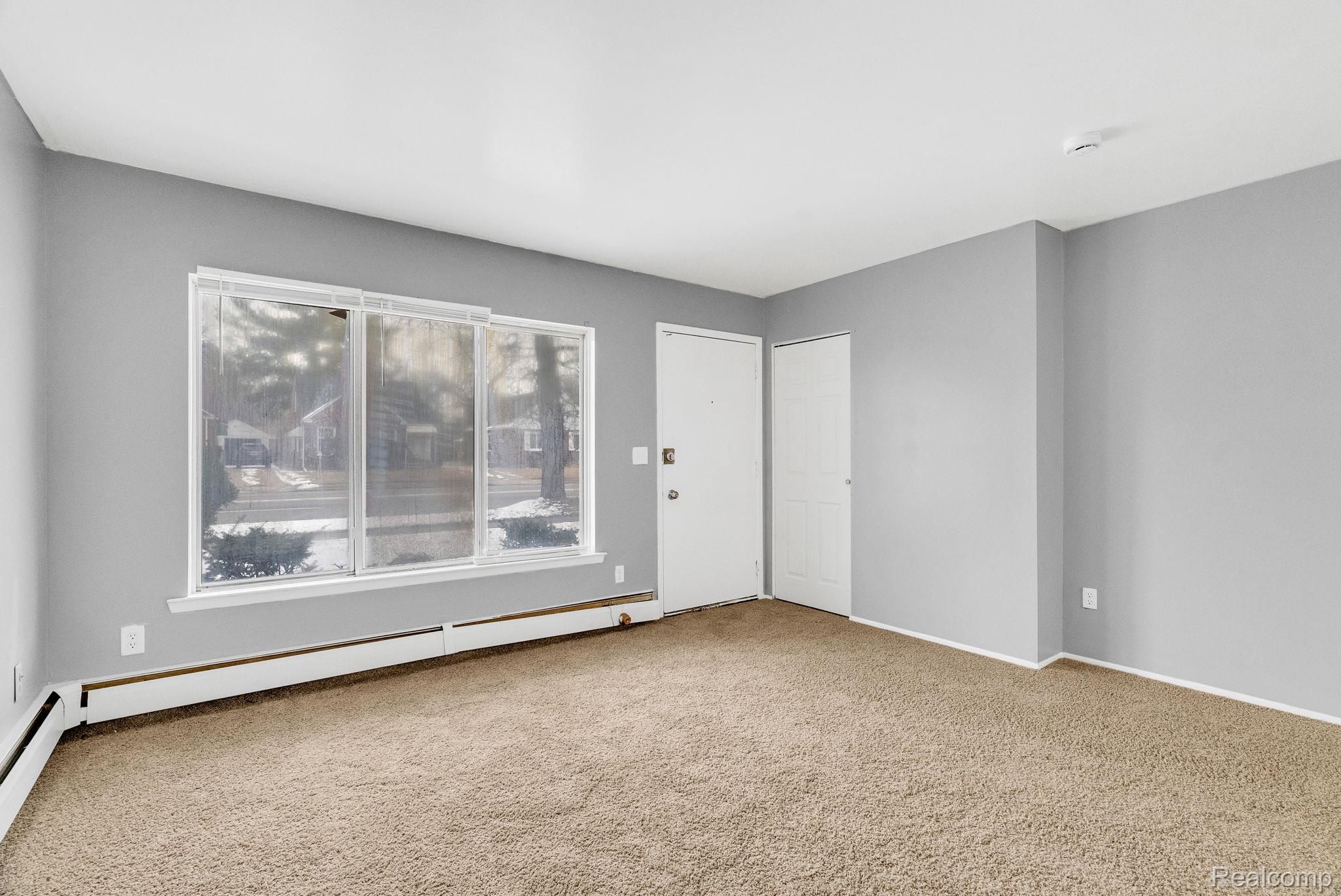 4535 Cadieux Road, Unit 42 / 210 Detroit, MI 48224 - Photo 6 of 16 Empty room featuring light carpet and baseboard heating
