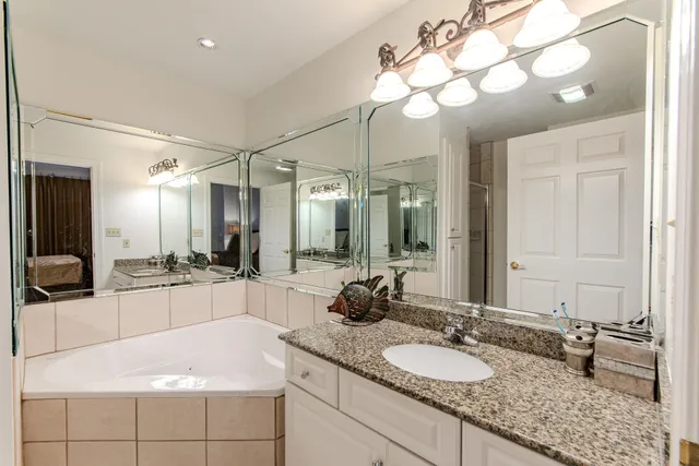 a bathroom with a granite countertop sink a large mirror and a bathtub