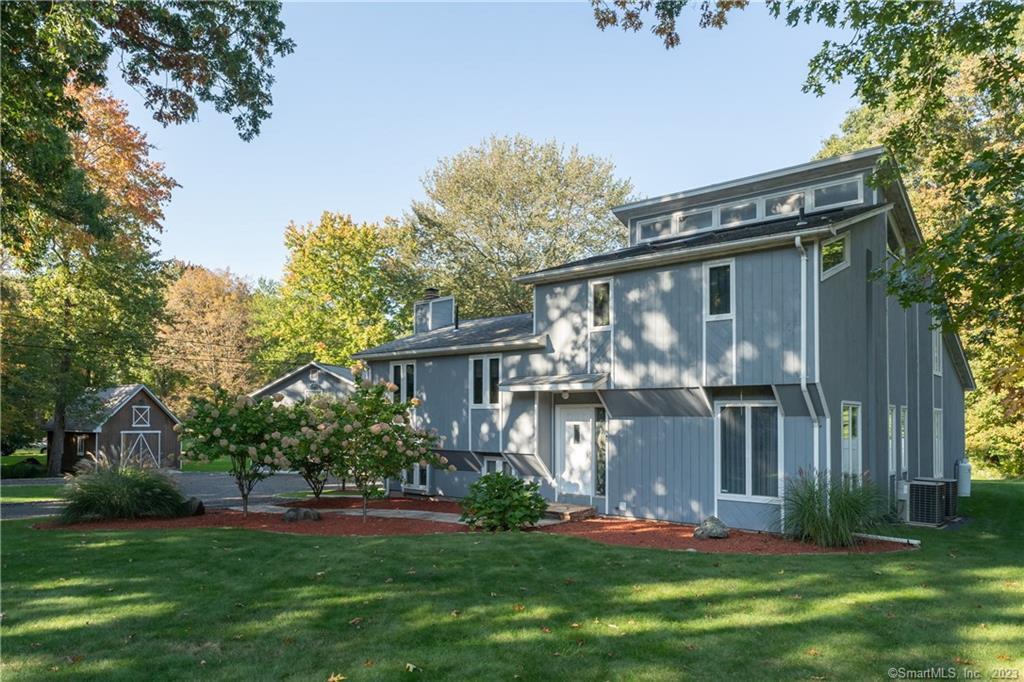 a front view of a house with a yard and a tree