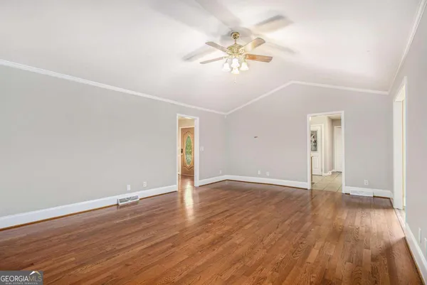 an empty room with wooden floor and chandelier fan