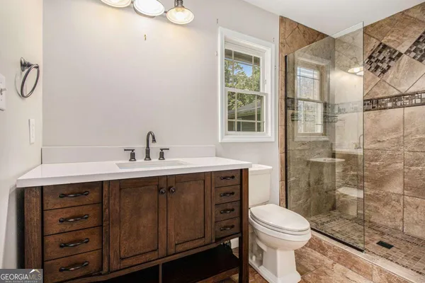 a bathroom with a sink a toilet and shower