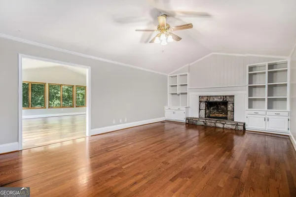 an empty room with wooden floor fireplace and windows