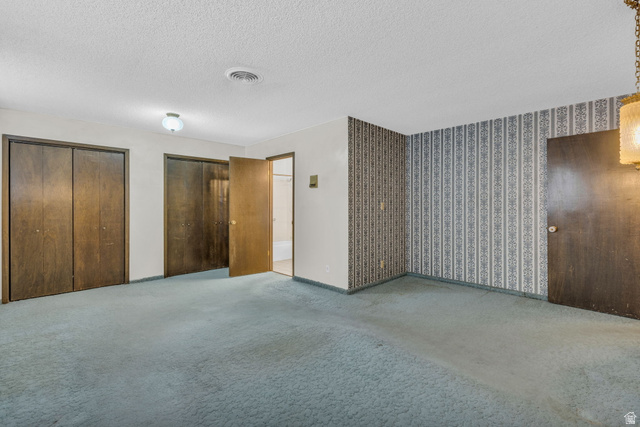 10705 Green Ridge Drive Sandy, UT 84070 - Photo 15 of 55 Unfurnished bedroom with multiple closets, carpet floors, and a textured ceiling