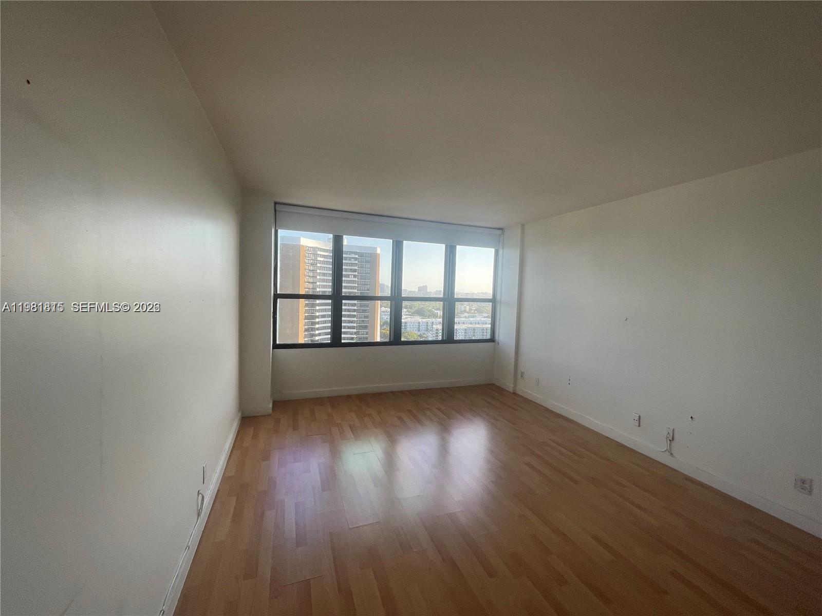 780 Northeast 69th Street, Unit 2201 Miami, FL 33138 - Photo 11 of 15 wooden floor in an empty room with a window