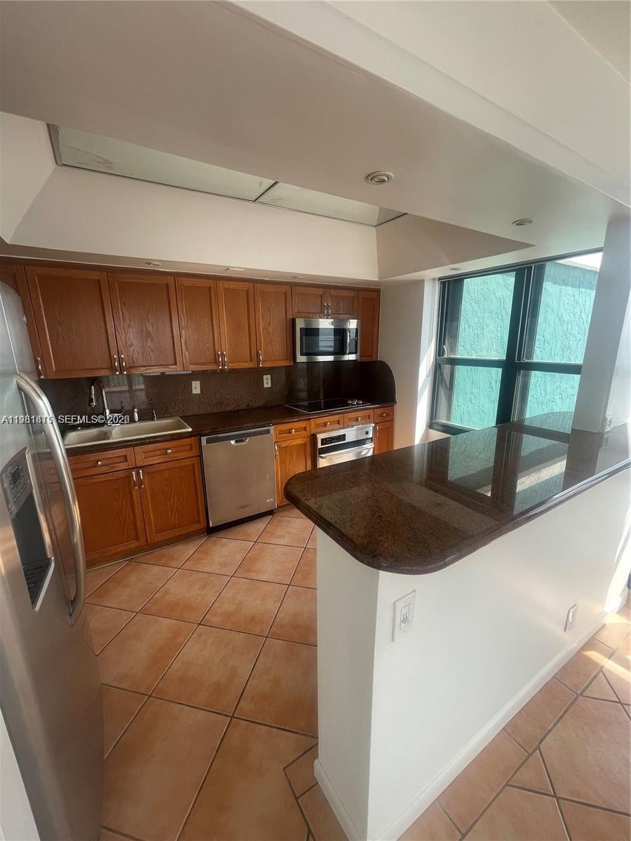 780 Northeast 69th Street, Unit 2201 Miami, FL 33138 - Photo 6 of 15 a kitchen with a sink a stove and cabinets