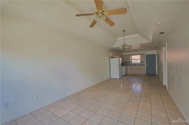 an empty room with chandelier fan and windows