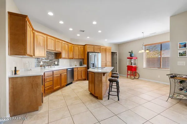 a kitchen with stainless steel appliances granite countertop a table chairs and a refrigerator