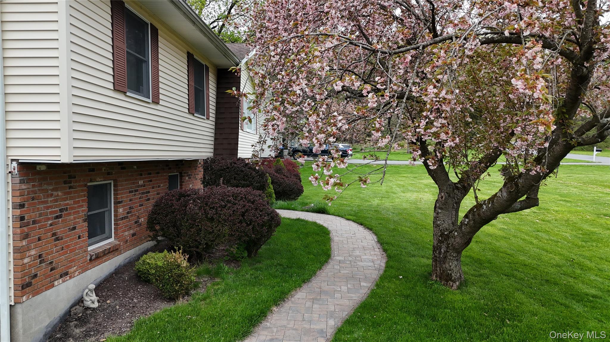 94 Booth Road Chester, NY 10918 - Photo 2 of 21 Charming paver stone winding pathway from the driveway to the front door flanked by a flowering tree with delicate pink blossoms and flower beds
