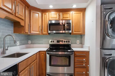 a kitchen with stainless steel appliances granite countertop a refrigerator a sink dishwasher a stove and white cabinets with wooden floor