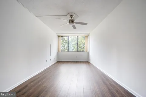 an empty room with wooden floor fan and windows