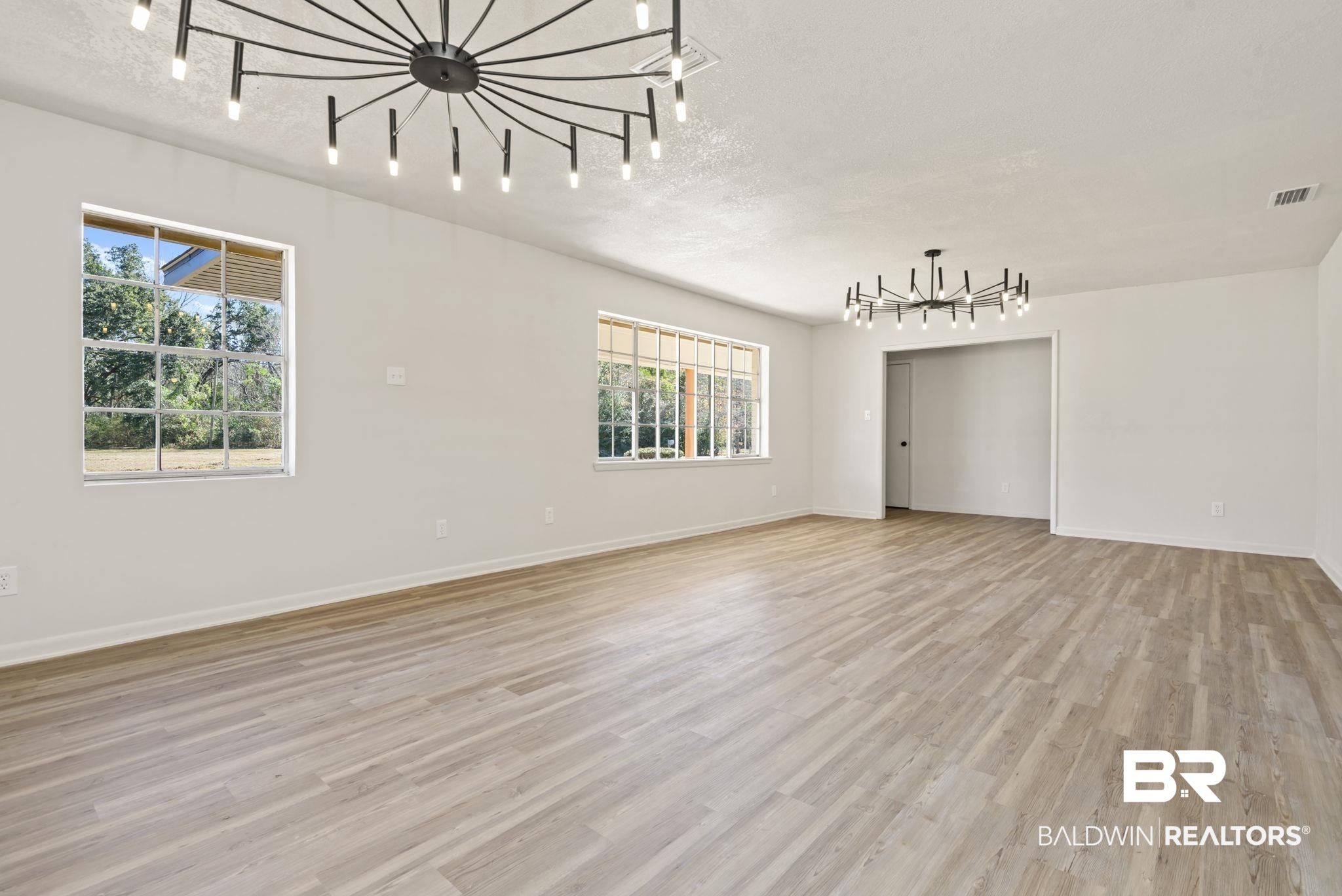 910 Moran Street Bay Minette, AL 36507 - Photo 2 of 20 Spare room with hanging lights, light wood-style flooring, and a textured ceiling