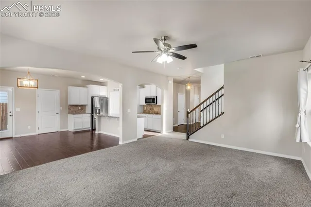 a view of a big room with windows and chandelier fan