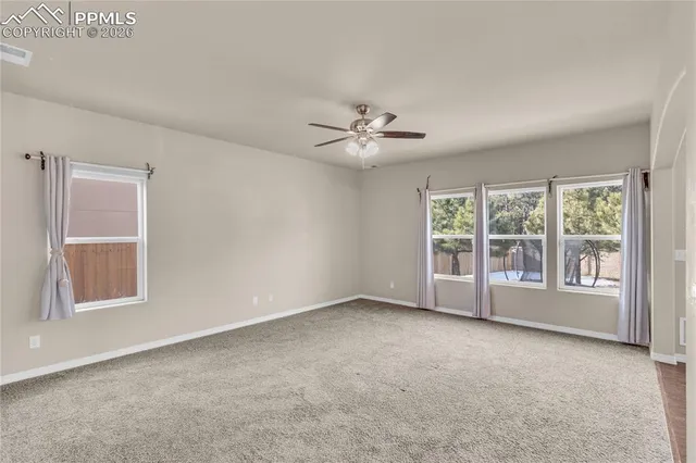 an empty room with ceiling fan and windows