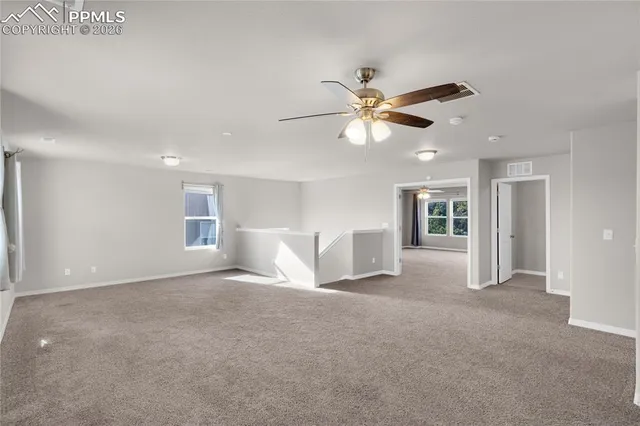 an empty room with a windows and chandelier fan